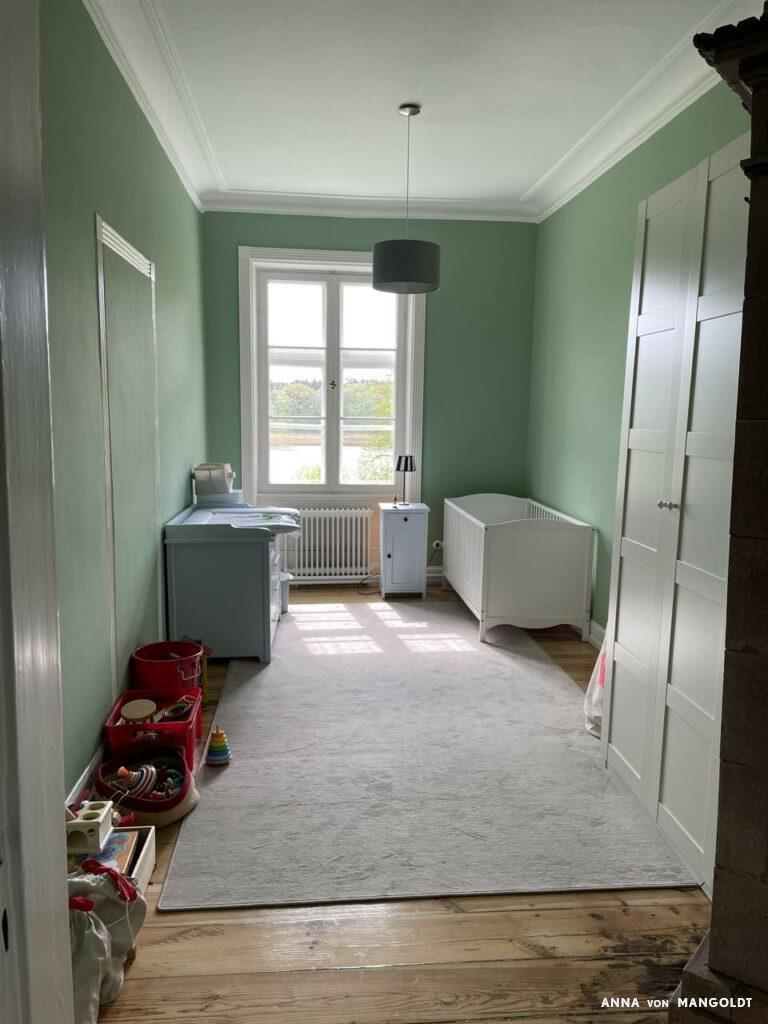 Blick in Kinderzimmer mit weißen Möbeln und Grünen Wänden